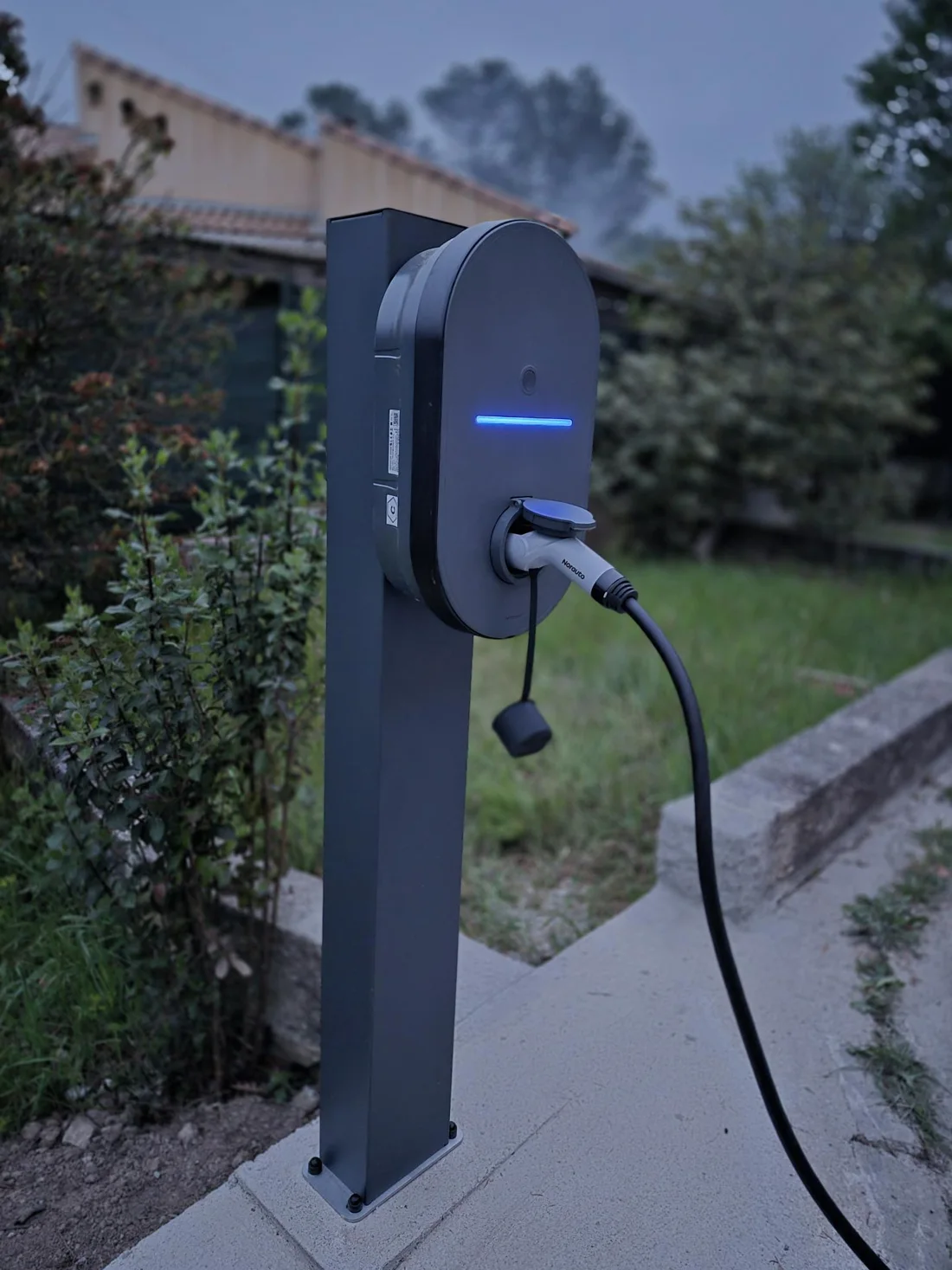 Borne de recharge fixée sur un totem dans le jardin d’une maison individuelle